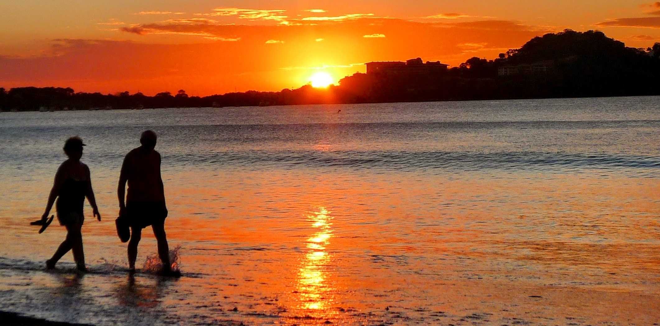 An elderly couple walking at the beach at sunset