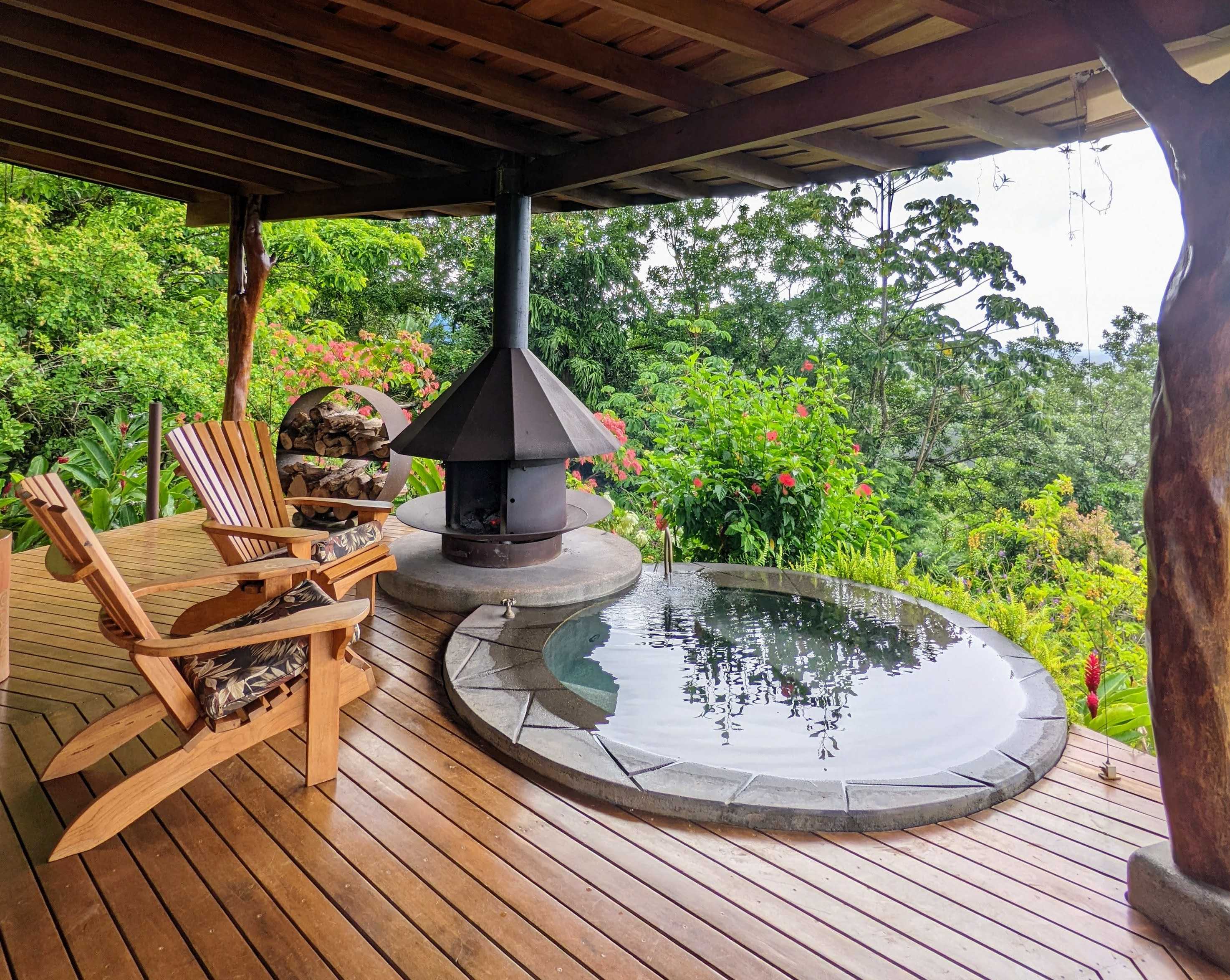 A deck with two chairs and a pool surrounded by trees