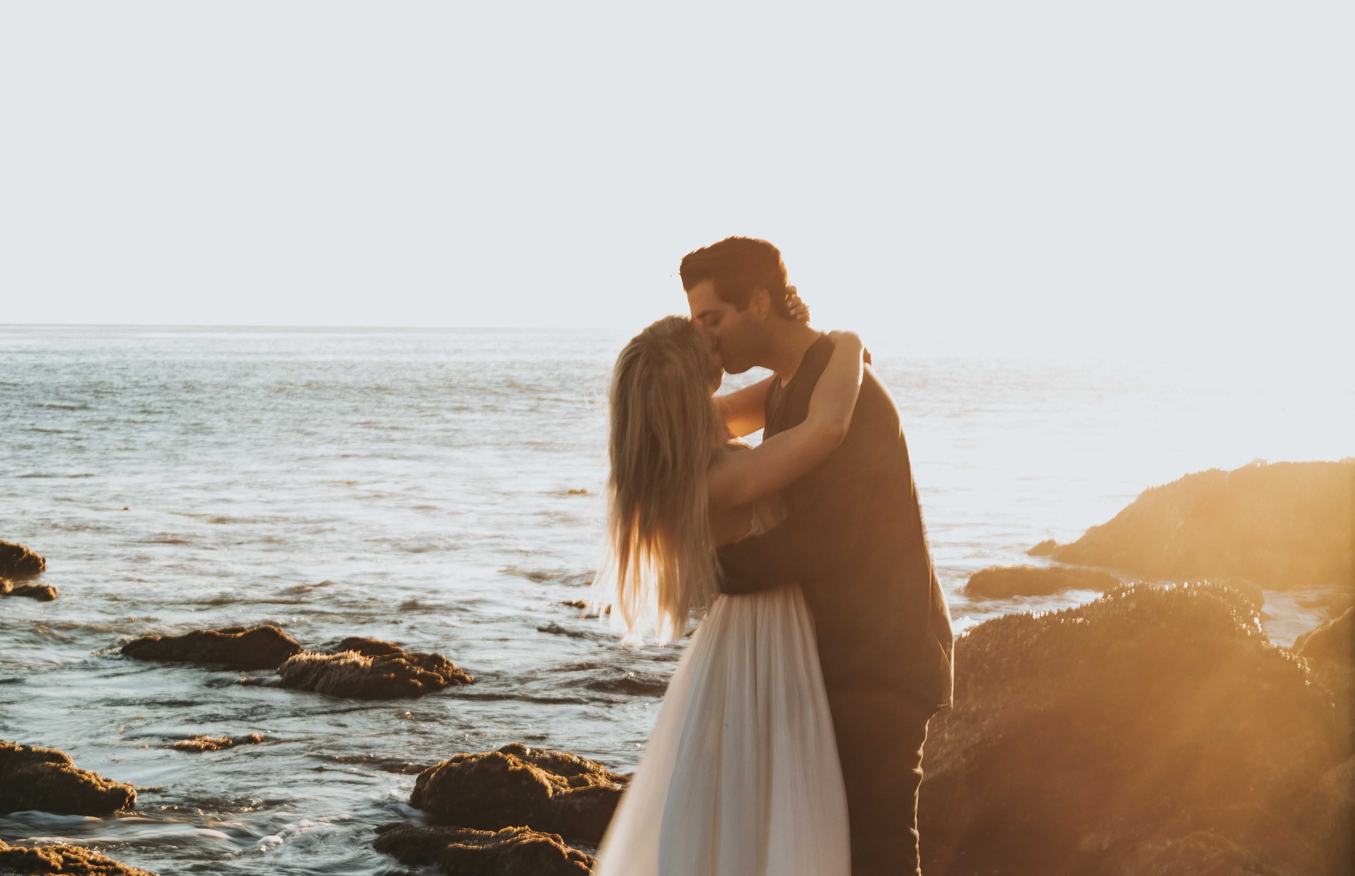 A newly married couple kissing at the beach